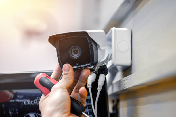 close up of surveillance camera installation, male hand holds cctv camera